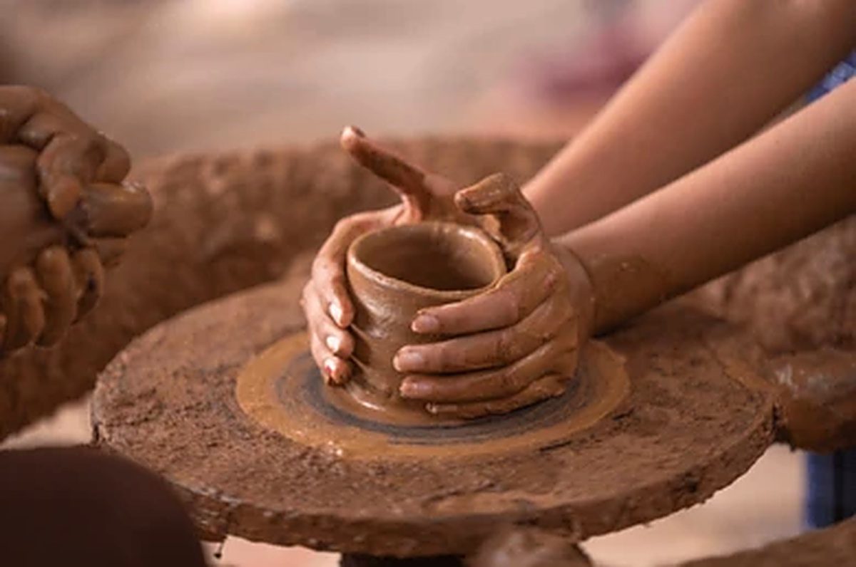 Hands shaping a pot on a potter's wheel